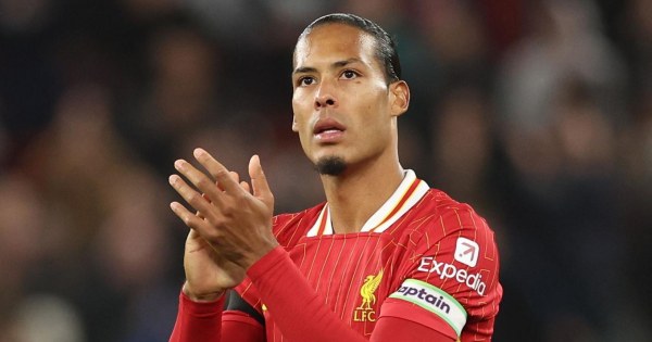 Tall defender heading ball confidently in crowded penalty area.